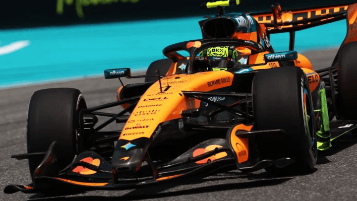 Voiture McLaren orange en action sur le circuit de Miami, vue de trois-quarts avant